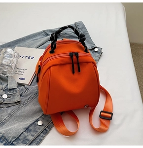 Detailopname van een oranje mini-rugzak in schelpvorm op een achtergrond van denim