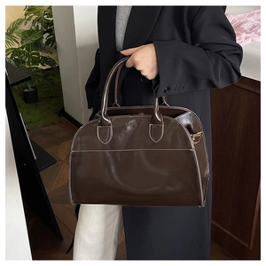 Detail of dark brown tote bag with white contrast stitching and shiny leather finish