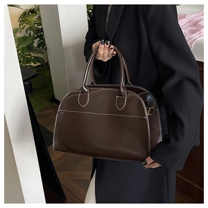 Detail of a dark brown vintage tote bag featuring contrasting white stitching and handles