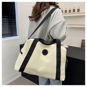 Detailed back view of a large cream travel bag with black straps and round logo patch