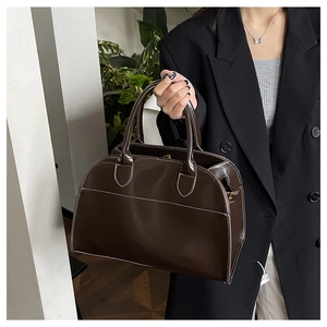 Detail of dark brown glossy leather tote with contrast stitching and dual handle design