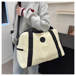 Detail of cream travel bag with black straps and adjustable shoulder strap attachment