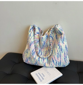 Detailaufnahme einer bunten Strick-Tote-Bag mit weißem Stoffetikett auf einer dunklen Fläche