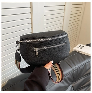 Detail of black pebbled leather crossbody bag with striped webbing strap and silver zippers