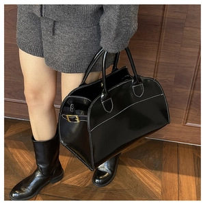 Detail of black tote bag featuring white contrast stitching and gold buckle accents