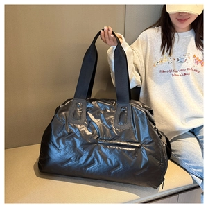 Detail of black quilted travel bag showing glossy texture and front zipper pocket