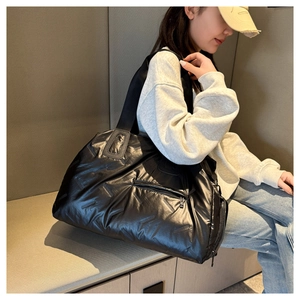 Asian model sitting with a large black quilted nylon gym bag and travel tote