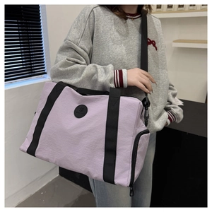 Detail of lavender travel bag with black straps and side zip pocket worn by model