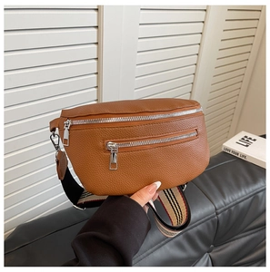 Detail of brown litchi pattern waist bag featuring dual silver zippers and striped strap
