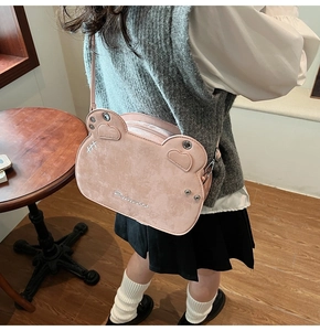Detail of pink cat-ear crossbody bag with Princess embroidery worn in casual style