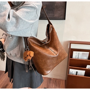Détail du sac cabas marron vintage avec texture brillante et breloque ours en peluche