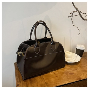 Detail of dark brown Boston tote bag with white contrast stitching and gold hardware