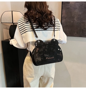 Close-up of black bear-shaped backpack with cat ears and Princess gold lettering