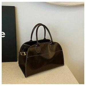Detailed view of dark brown leather Boston bag featuring prominent white stitching accents
