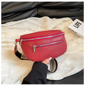 Detail of red lychee textured leather waist bag with striped strap and silver zippers