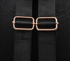Close-up of black lychee leather backpack showing rose gold metal adjustment buckles