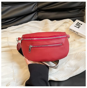 Detail of red lychee grain saddle bag featuring dual zippers and striped strap