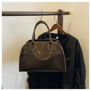 Close-up of a dark brown glossy leather tote bag with white contrast stitching detail