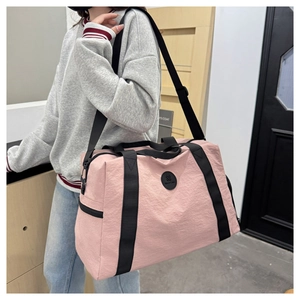 Detail of pink waterproof oxford travel bag with adjustable strap shown by model