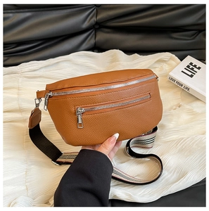 Close-up of brown litchi pattern leather saddle bag with striped woven strap details