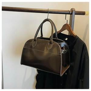 Detailed view of dark brown gloss doctor bag with contrast stitching and metal buckles