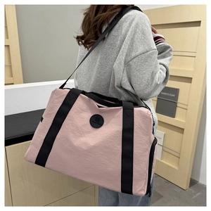 Detail view of pink Oxford travel bag with black straps and side zipper pocket