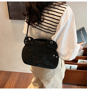 Black leather frog-shaped crossbody bag with Princess text on a model in a library setting