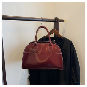 Detail of burgundy leather tote bag featuring contrast stitching and sturdy top handles
