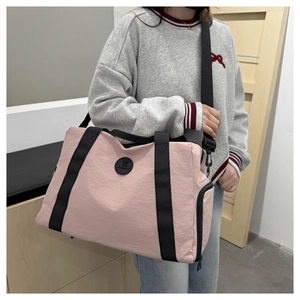 Detail of pink large capacity Oxford travel bag with black straps and side zip pocket