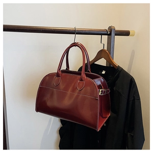 Close-up of wine red PU leather tote with detailed white stitching on a wooden hanger