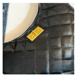 Gros plan sur le cuir noir matelassé et le fermoir doré tournant de ce sac élégant