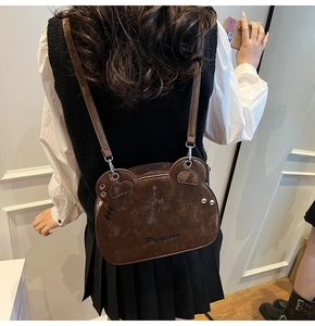 Detail of brown bear-shaped crossbody bag featuring suede texture and Princess embroidery