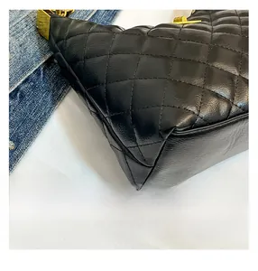 Gros plan sur la texture en cuir noir matelassé et les finitions dorées du sac
