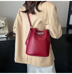 Detailed close-up of dark red lychee leather bucket bag with silver buckle and strap