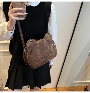 Detail of cute bear-shaped crossbody bag in vintage brown leather with Princess text