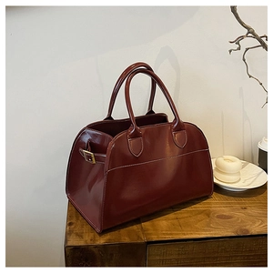 Close-up of a burgundy tote bag featuring bold white contrast stitching and shiny finish