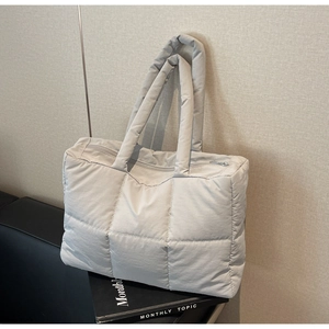 Detailed close-up of a large light grey quilted puffer tote bag with zipper closure