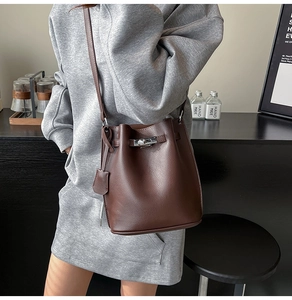Detail of dark brown pebble leather bucket bag featuring a silver twist-lock closure