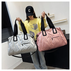 Detail of quilted metallic duffel bags in silver and pink with adjustable straps