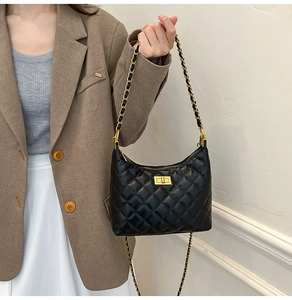 Détail d'un sac à bandoulière matelassé noir avec chaîne dorée et fermoir pivotant