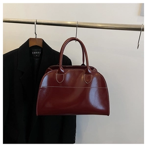 Macro view of burgundy tote bag showing vintage white contrast stitching and smooth leather finish