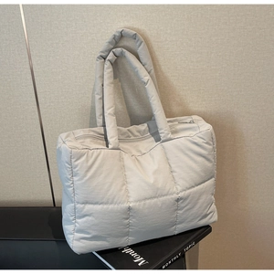Close-up of quilted puffer tote bag with padded handles and secure zipper closure detail