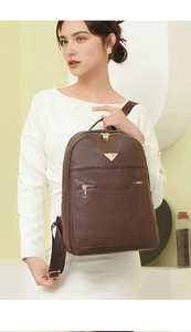 Detail of dark brown pebble leather backpack with gold metal triangle plaque on model