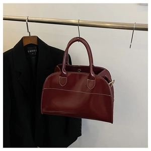 Close-up of wine red patent leather tote bag with distinctive white contrast stitching
