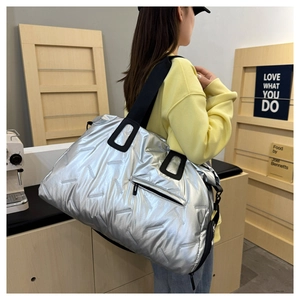 Close-up of quilted metallic silver travel tote bag with black straps and zippered pocket