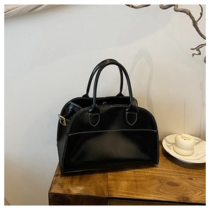 Close-up of black leather tote bag featuring detailed white contrast stitching and gold metal hardware