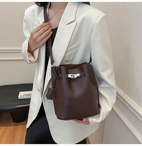 Detail of a dark brown leather bucket bag with silver buckles and a thin shoulder strap