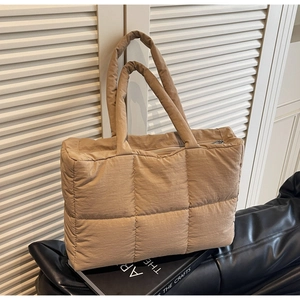Detail of khaki quilted puffer tote bag with padded handles and secure metal zipper