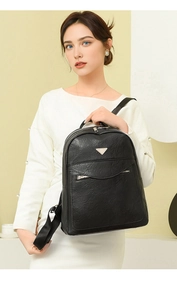 Macro detail of black vintage leather texture and metallic triangle plaque on backpack