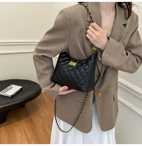 Gros plan du sac bandoulière en cuir matelassé noir avec chaîne dorée porté par un mannequin